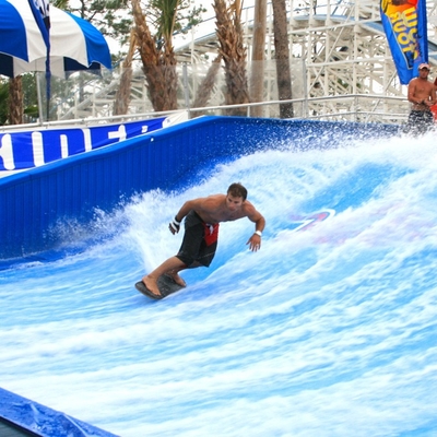 Disfrutando de paseo del agua de Flowrider, el tablero atractivo/la aguamarina de la resbalón de la onda que practica surf parquea la diversión